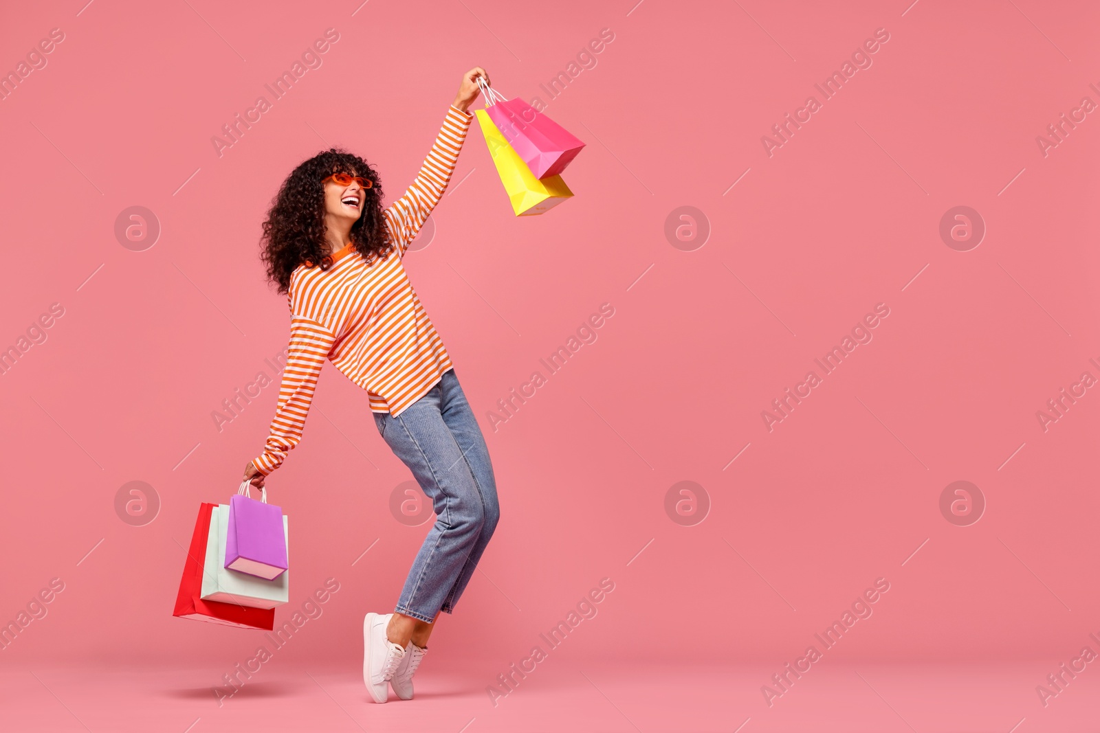 Photo of Happy woman with colorful shopping bags on pink background. Space for text