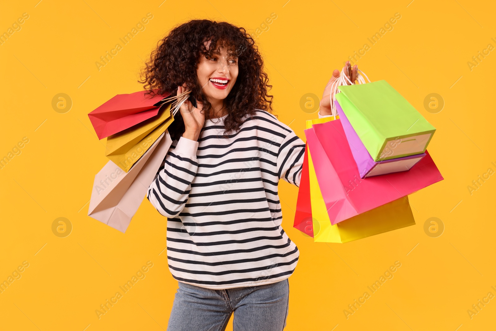 Photo of Smiling woman with colorful shopping bags on yellow background