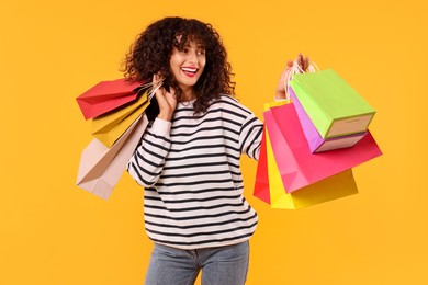 Smiling woman with colorful shopping bags on yellow background