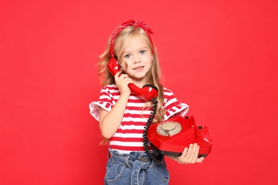 Photo of Cute little girl with telephone on red background