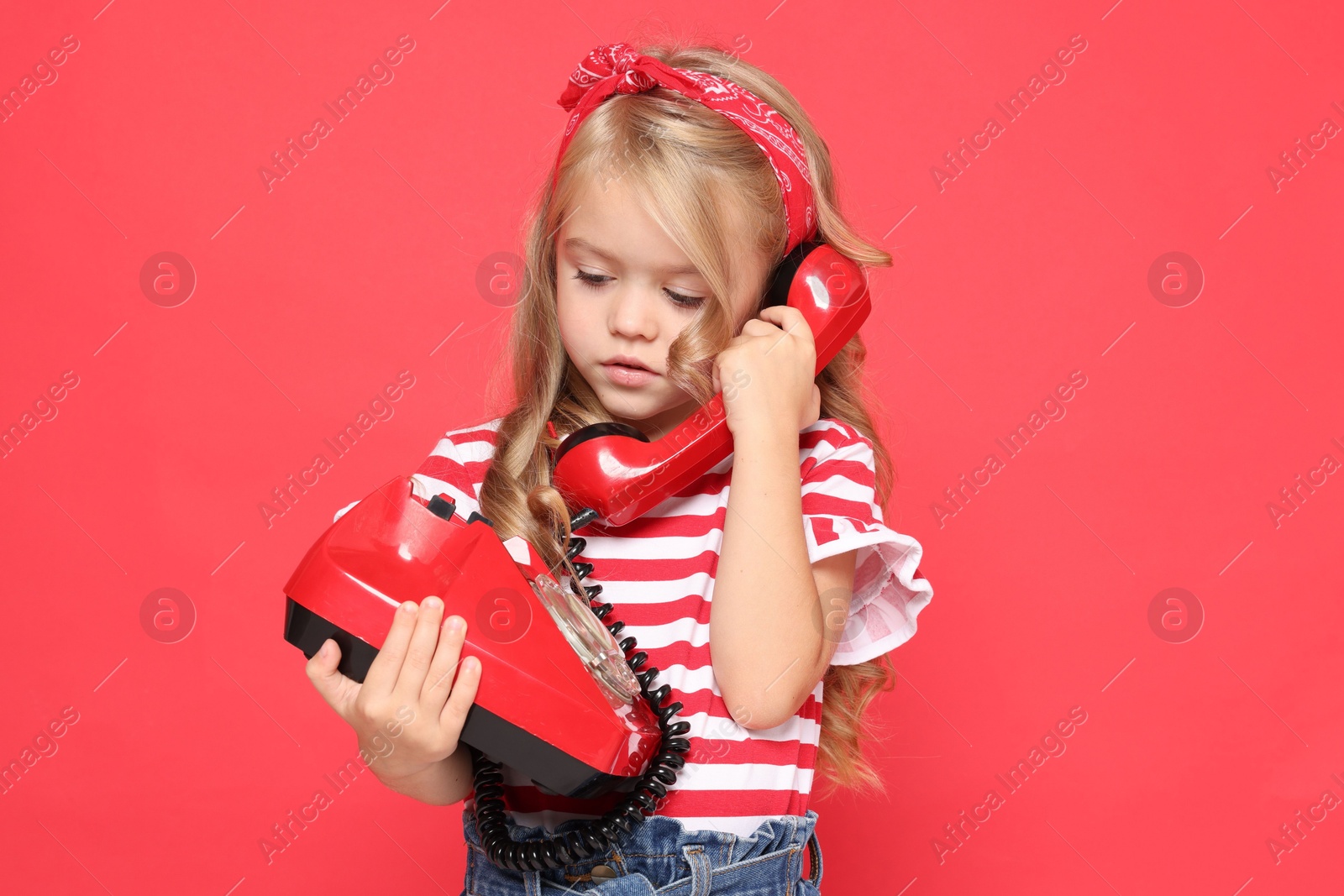 Photo of Cute little girl with telephone on red background