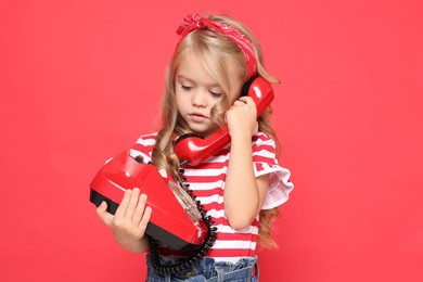 Photo of Cute little girl with telephone on red background