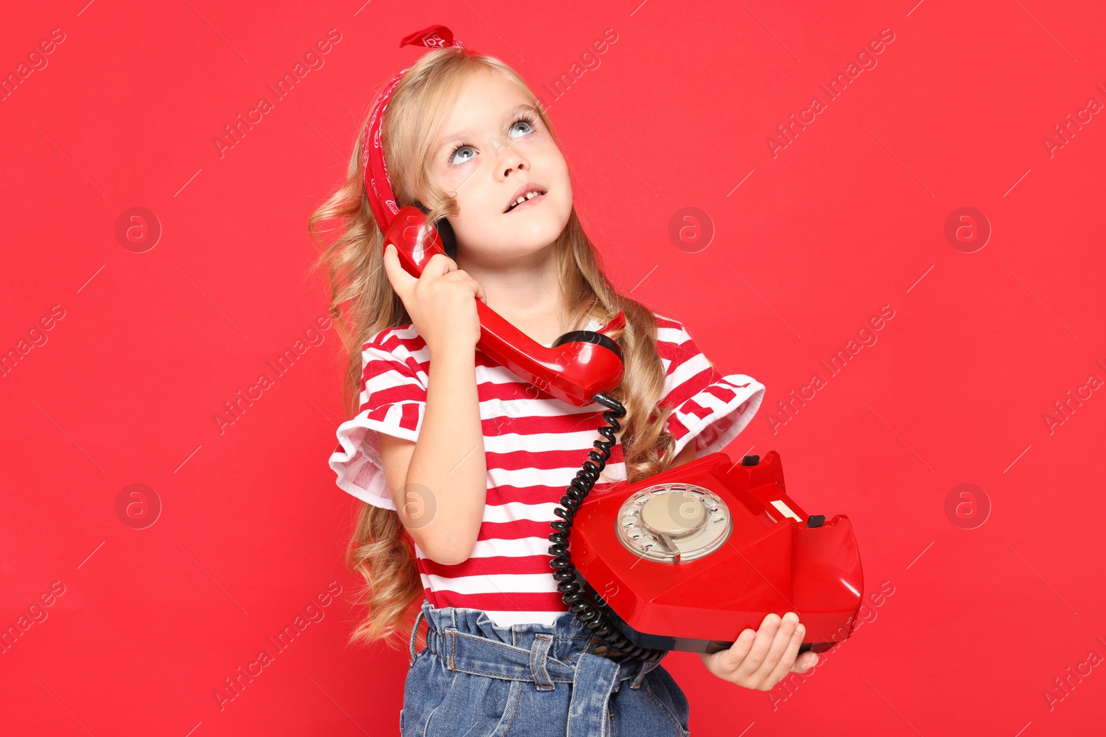 Photo of Cute little girl with telephone on red background