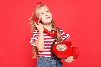 Cute little girl with telephone on red background