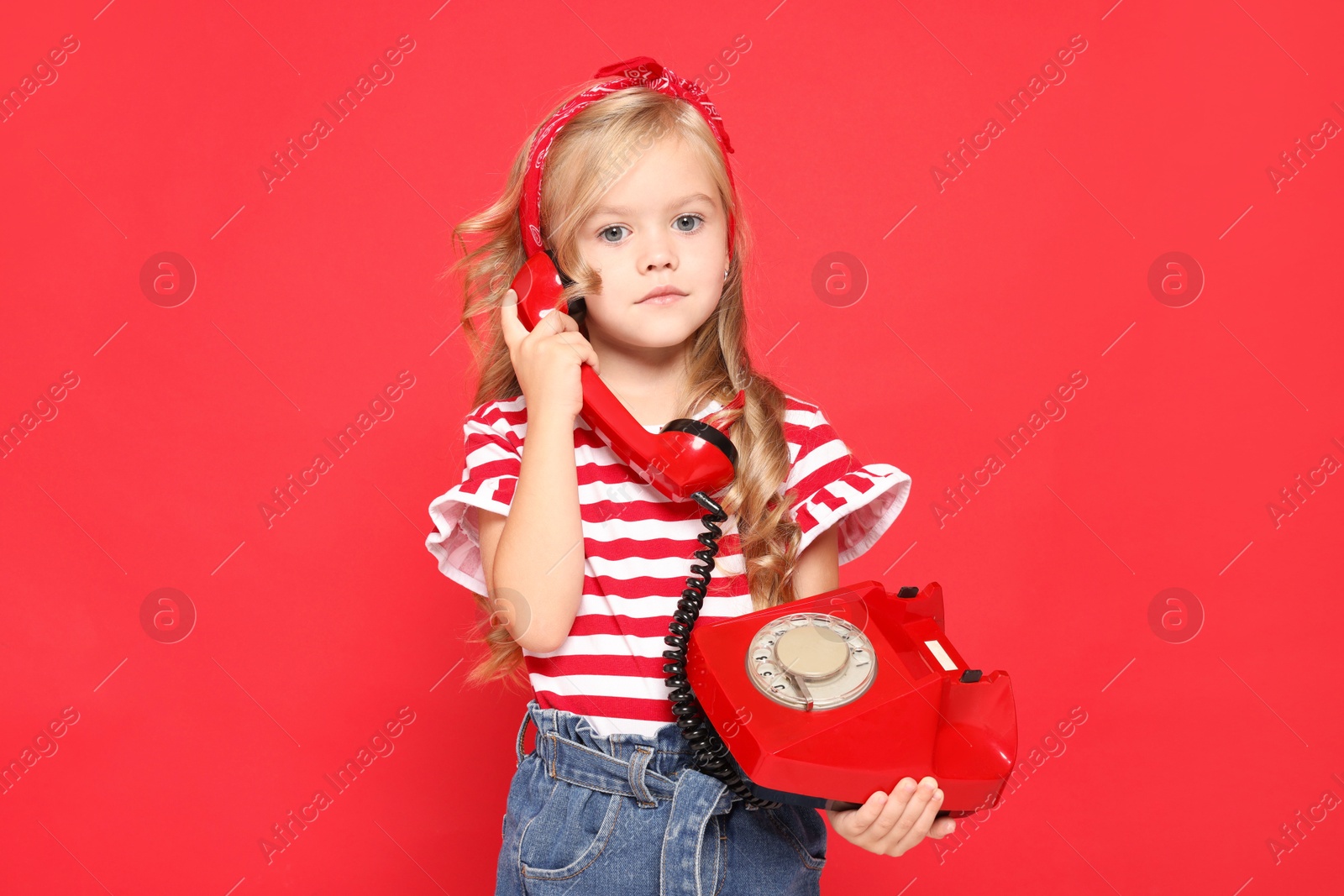 Photo of Cute little girl with telephone on red background