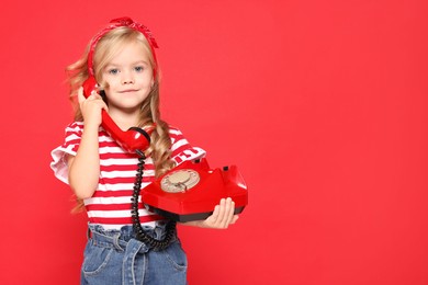 Photo of Cute little girl with telephone on red background, space for text