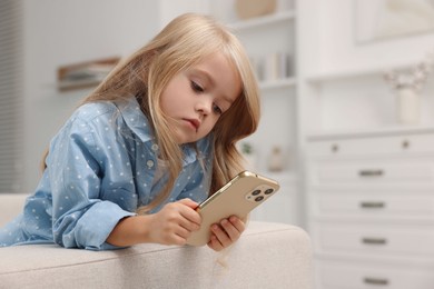 Cute little girl using smartphone at home