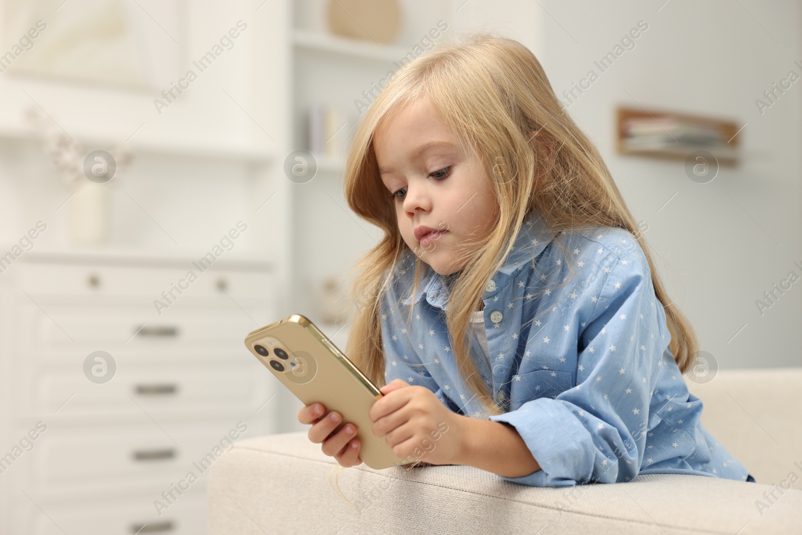 Photo of Cute little girl using smartphone at home