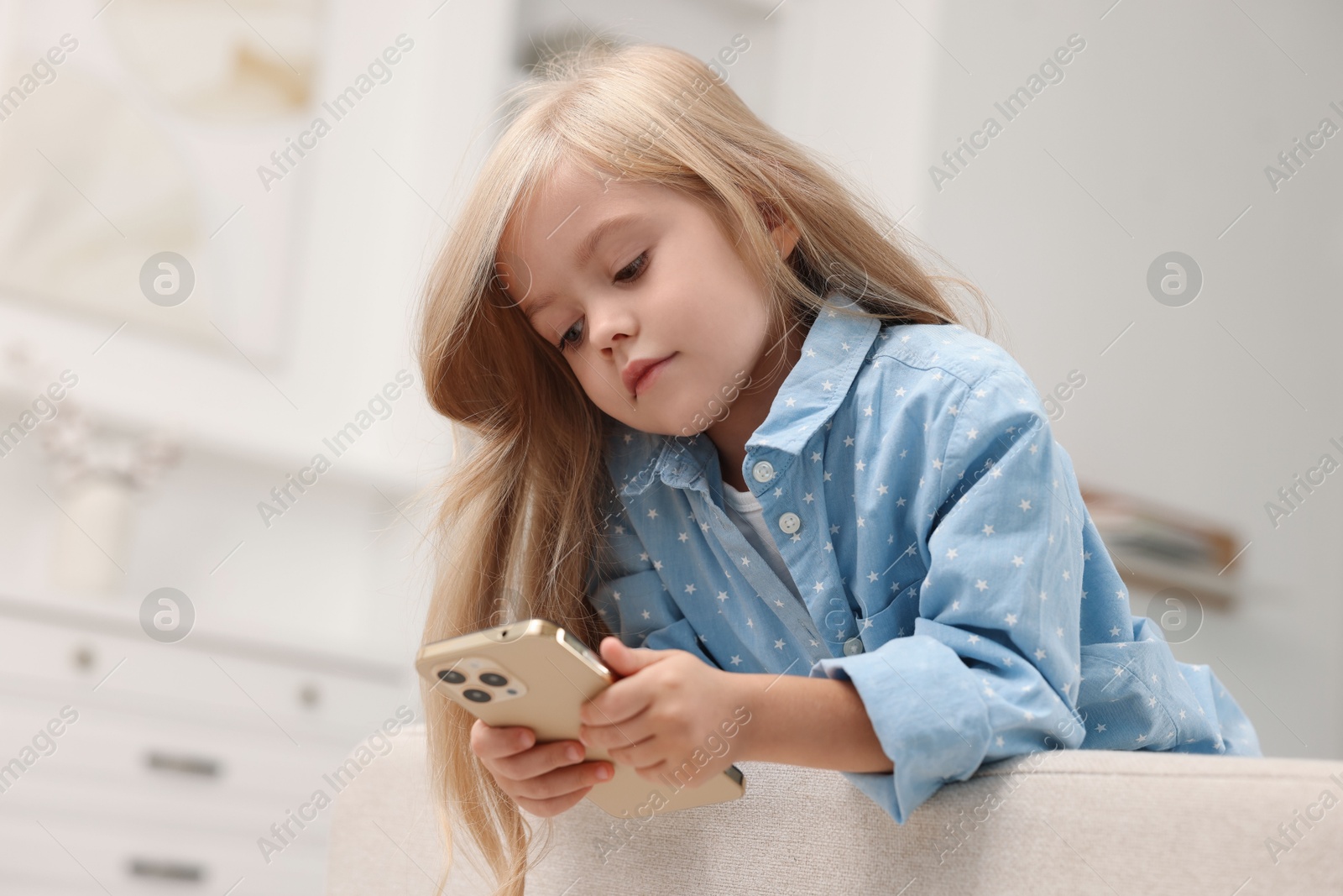 Photo of Cute little girl using smartphone at home