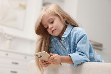 Cute little girl using smartphone at home