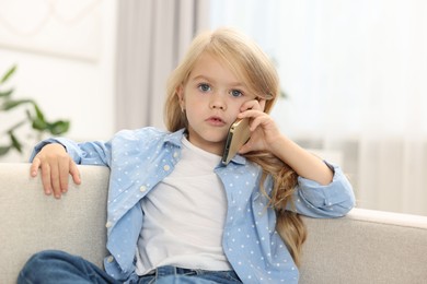 Photo of Cute little girl talking on smartphone at home