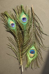 Photo of Many beautiful peacock feathers on light brown background, top view