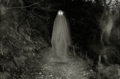 Image of Scary ghost with glowing eyes on pathway in forest