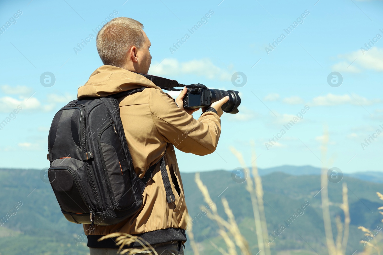 Photo of Photographer with backpack and camera taking picture of beautiful mountains