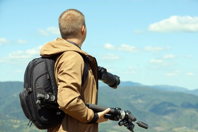 Photo of Photographer with backpack, camera and other professional equipment in mountains