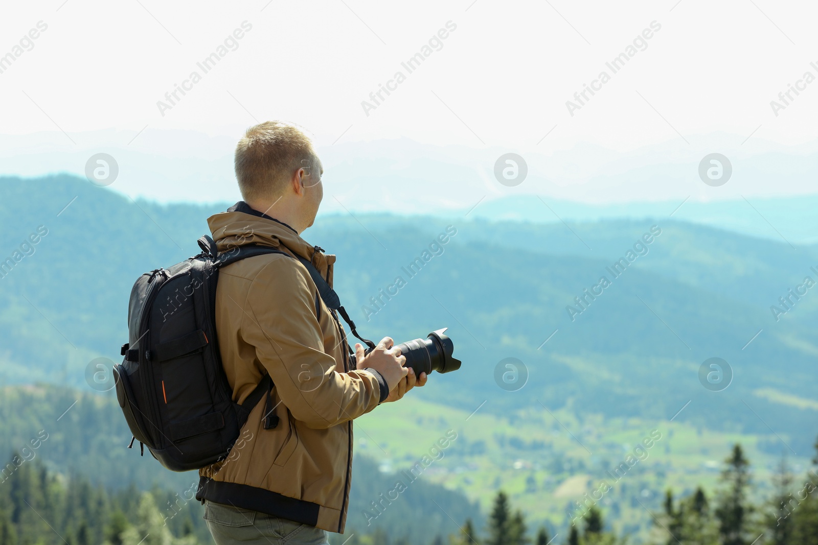 Photo of Photographer with backpack and camera taking picture of beautiful mountains. Space for text