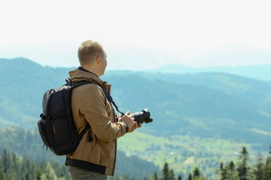 Photographer with backpack and camera taking picture of beautiful mountains. Space for text