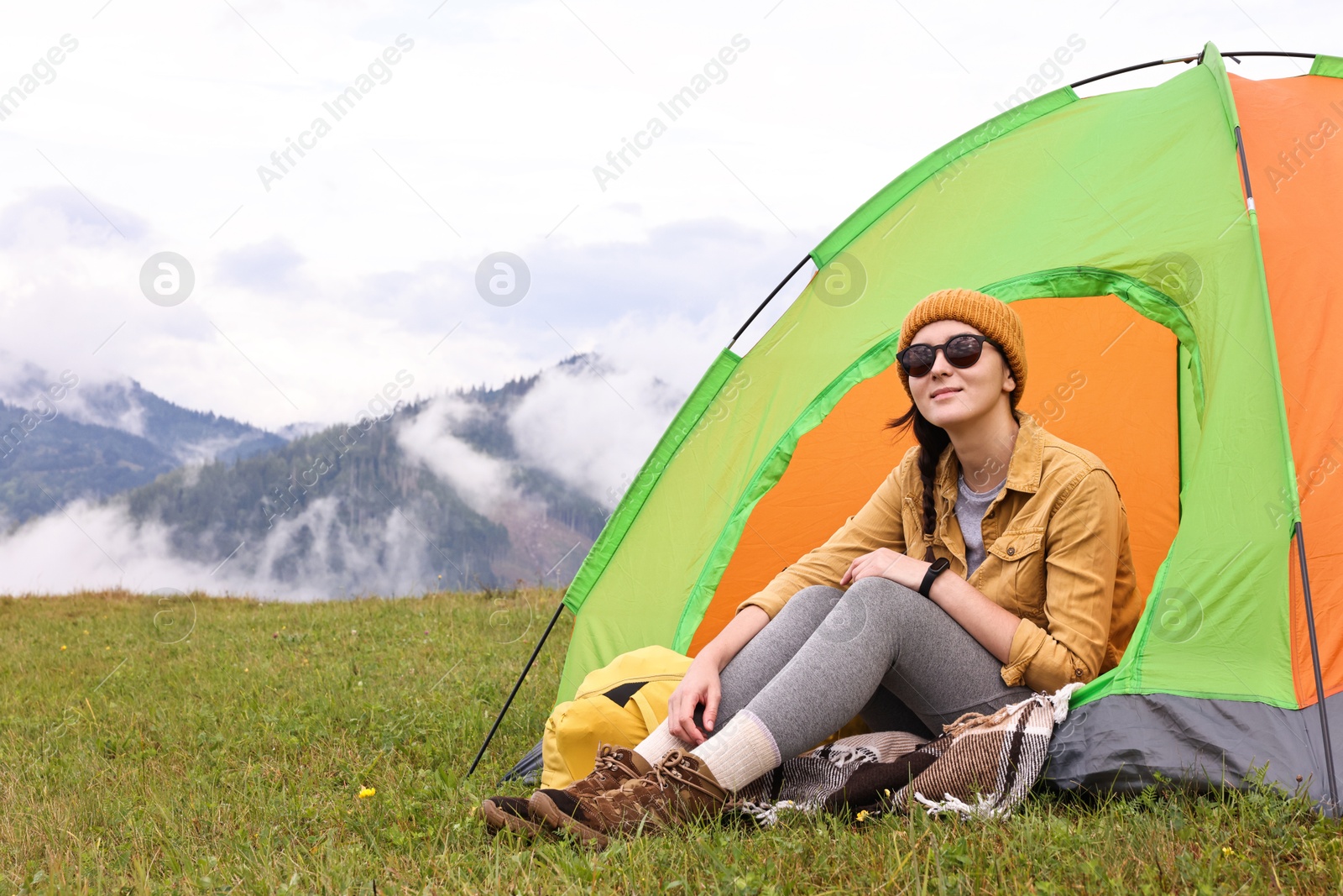 Photo of Young camper and tent in mountains. Active tourism