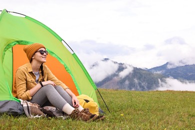 Photo of Young camper and tent in mountains. Active tourism