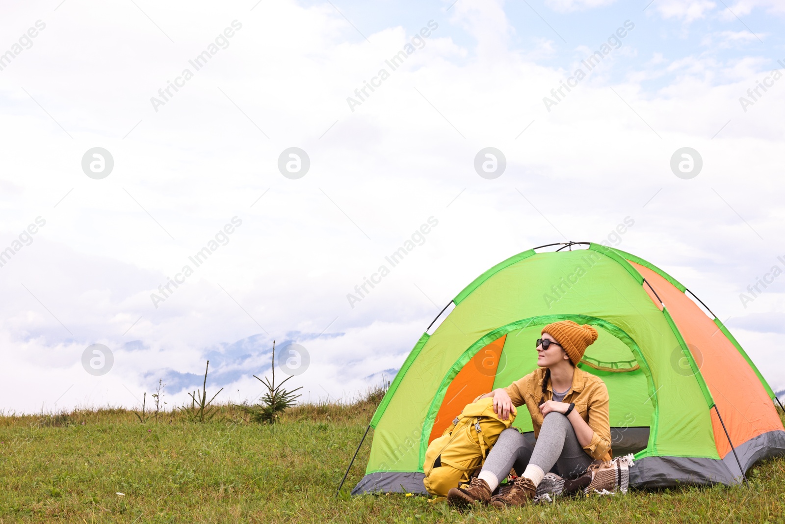 Photo of Young camper and tent in mountains. Active tourism