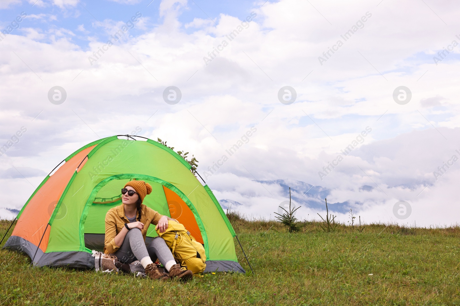 Photo of Young camper and tent in mountains. Active tourism