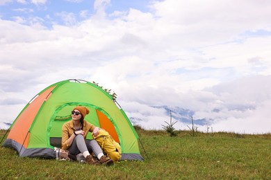 Photo of Young camper and tent in mountains. Active tourism