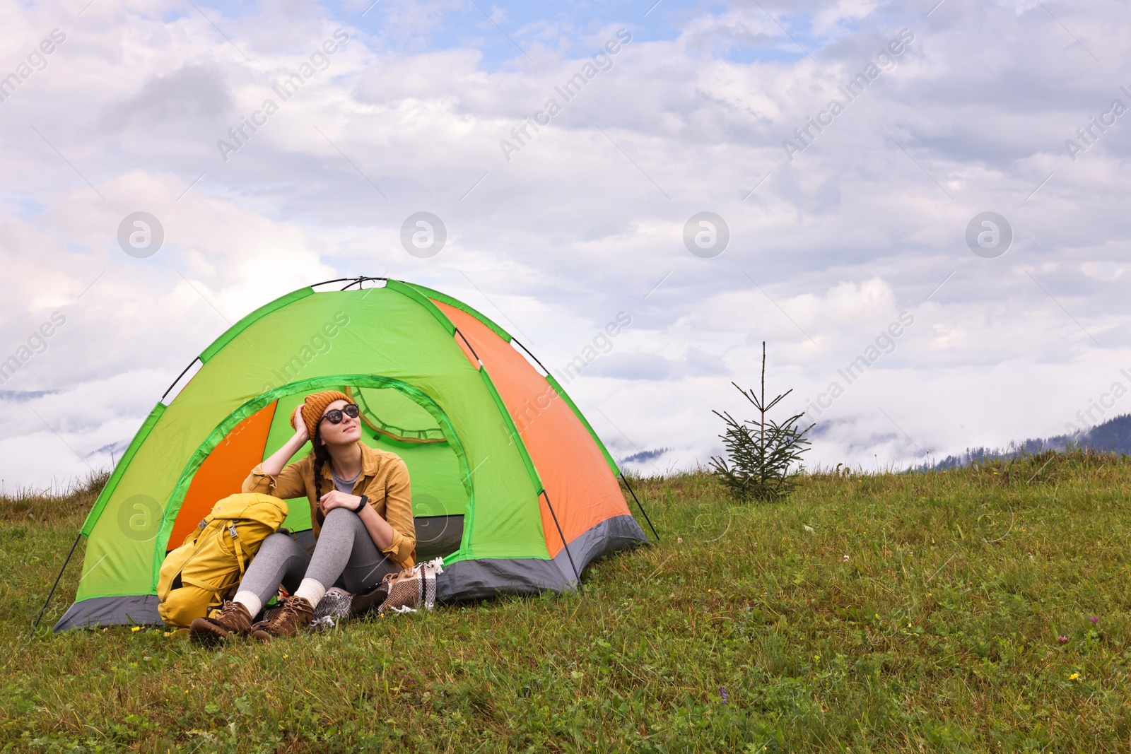 Photo of Young camper and tent in mountains. Active tourism