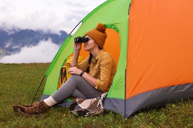 Photo of Young camper and tent in mountains. Active tourism