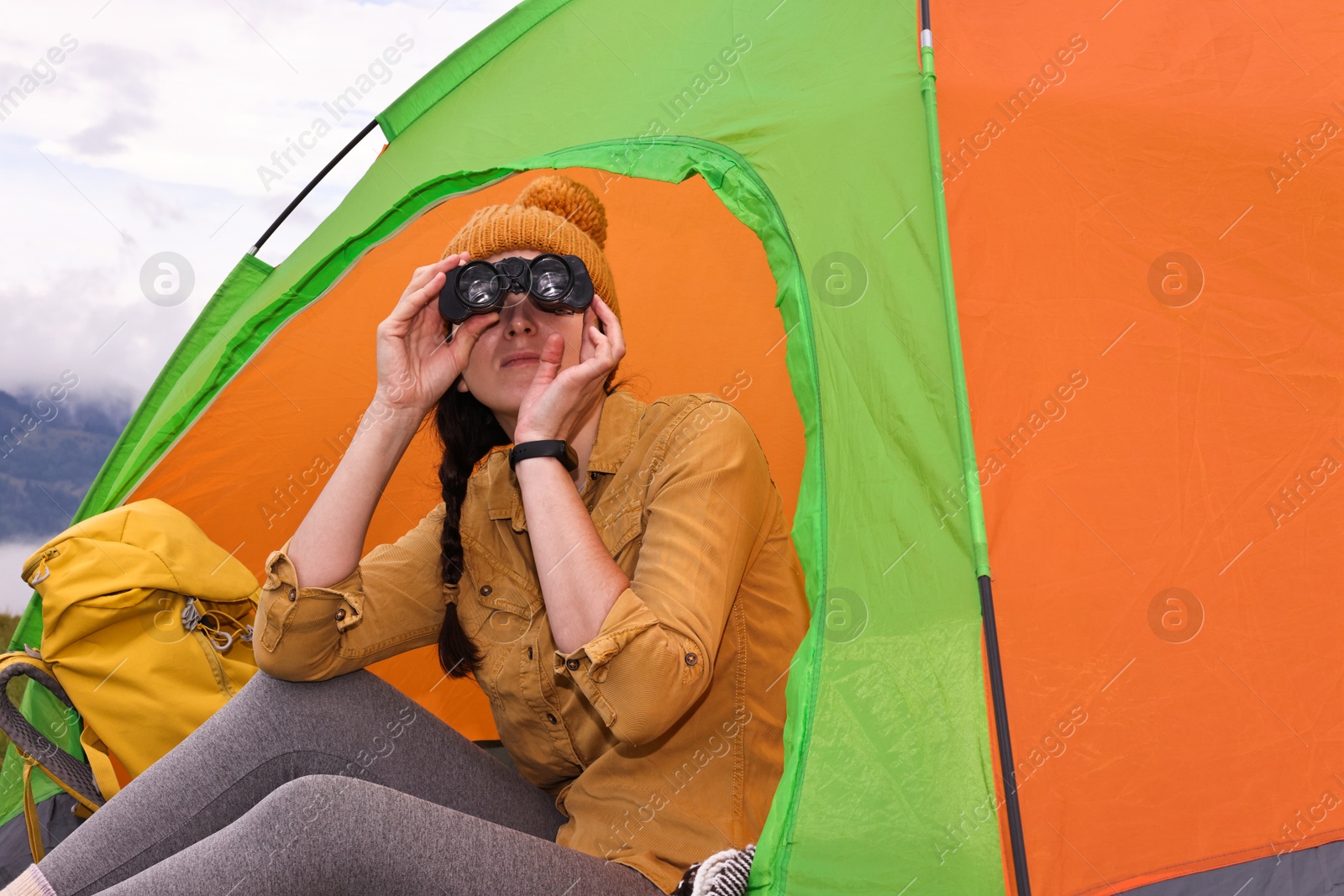 Photo of Young camper and tent in mountains. Active tourism