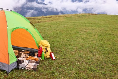 Photo of Tent, backpack and camping equipment on green grass in mountains, space for text