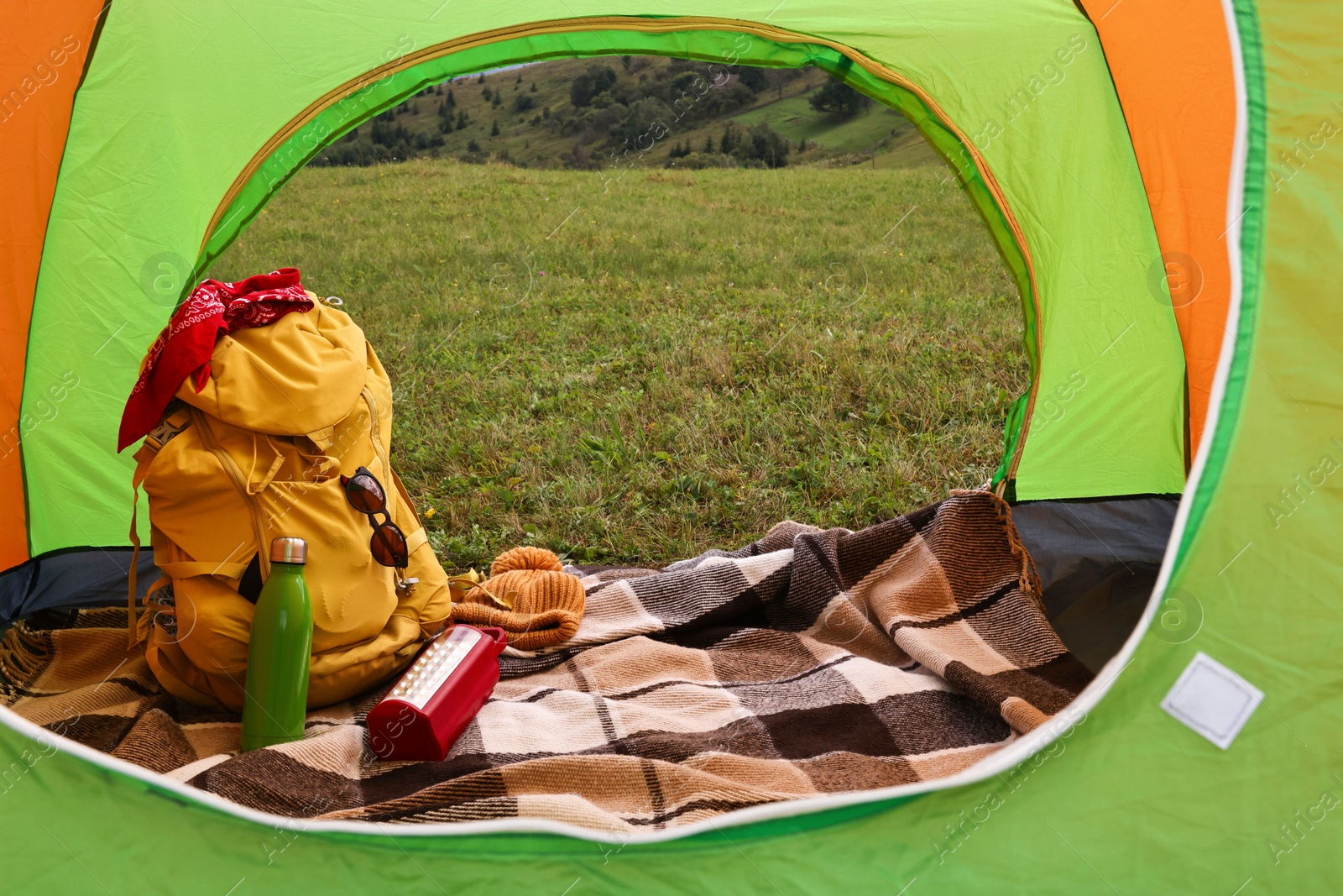 Photo of Tent, backpack and camping equipment on green grass in mountains