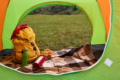 Tent, backpack and camping equipment on green grass in mountains