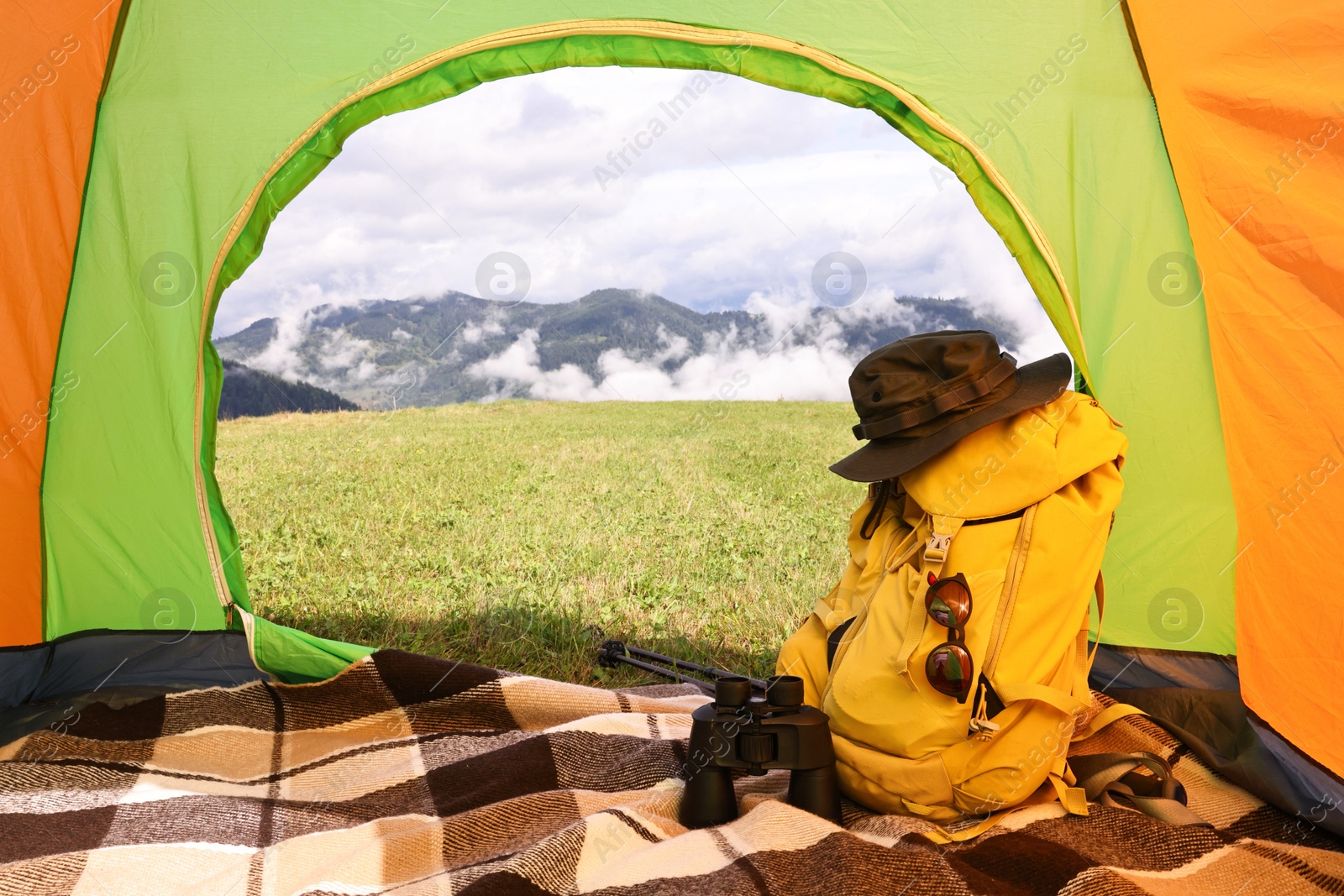 Photo of Tent, backpack and camping equipment on green grass in mountains