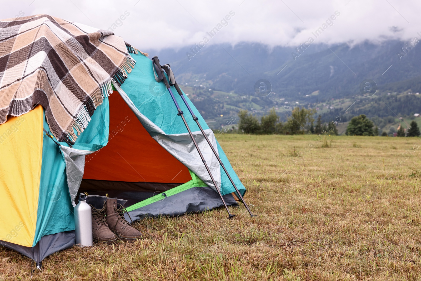 Photo of Camping tent and tourist stuff on grass in mountains, space for text