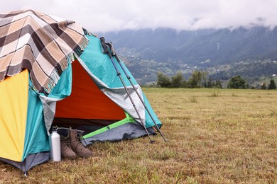 Photo of Camping tent and tourist stuff on grass in mountains, space for text