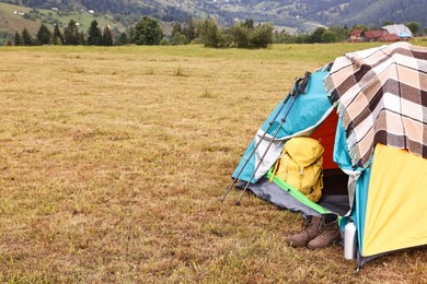 Photo of Camping tent and tourist stuff on grass in mountains, space for text