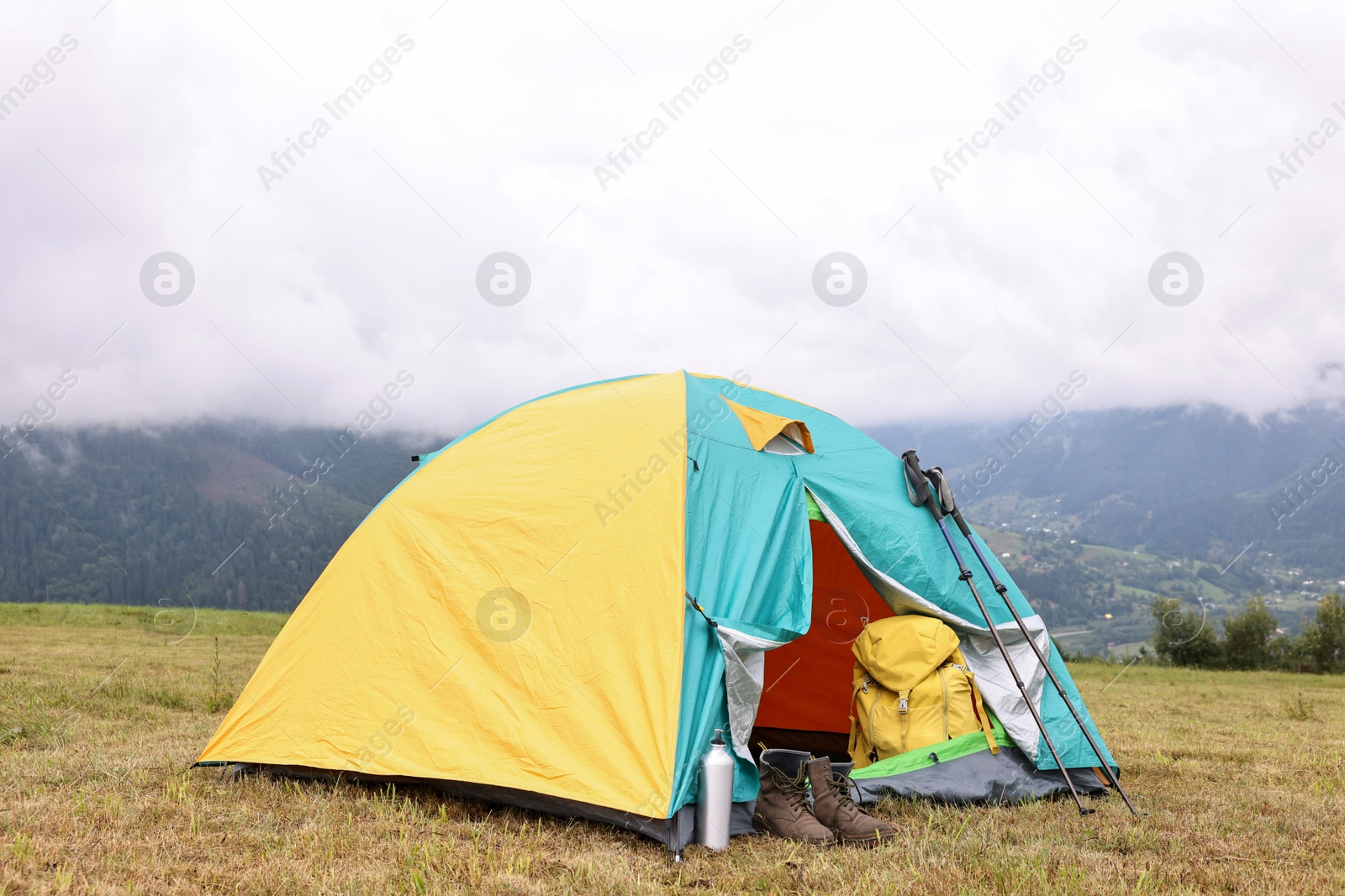 Photo of Camping tent and tourist stuff on grass in mountains