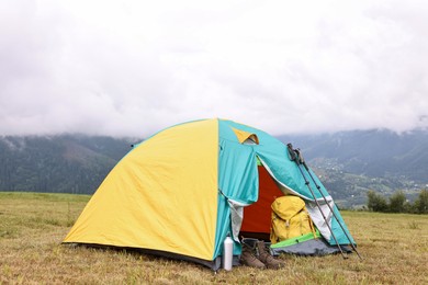 Photo of Camping tent and tourist stuff on grass in mountains