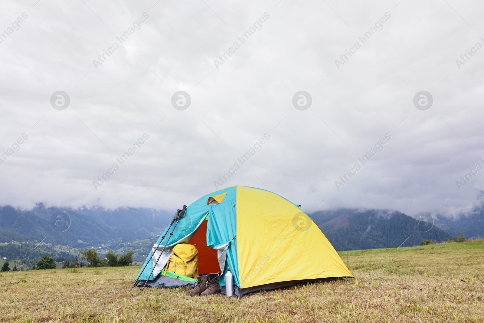 Photo of Camping tent and tourist stuff on grass in mountains