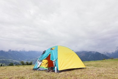 Camping tent and tourist stuff on grass in mountains