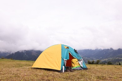 Photo of Camping tent and tourist stuff on grass in mountains