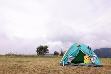 Camping tent and tourist stuff on grass in mountains, space for text