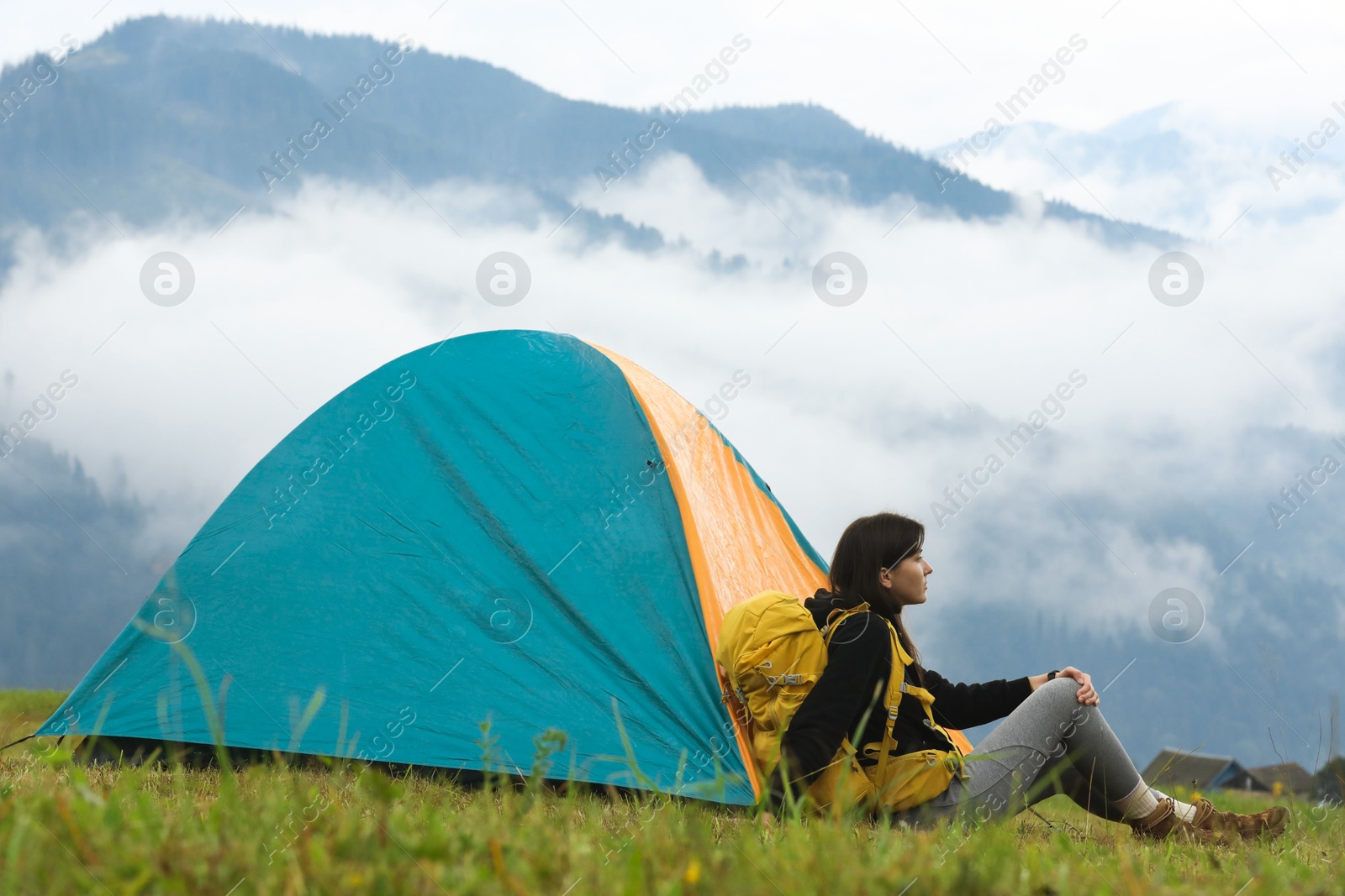 Photo of Young camper with backpack and tent in mountains