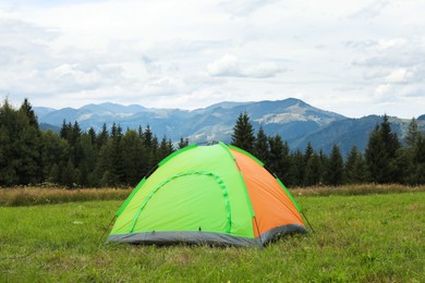 Tent on green grass in mountains. Camping equipment