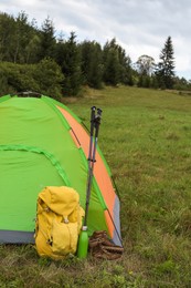 Photo of Tent, backpack and trekking poles on green grass in mountains