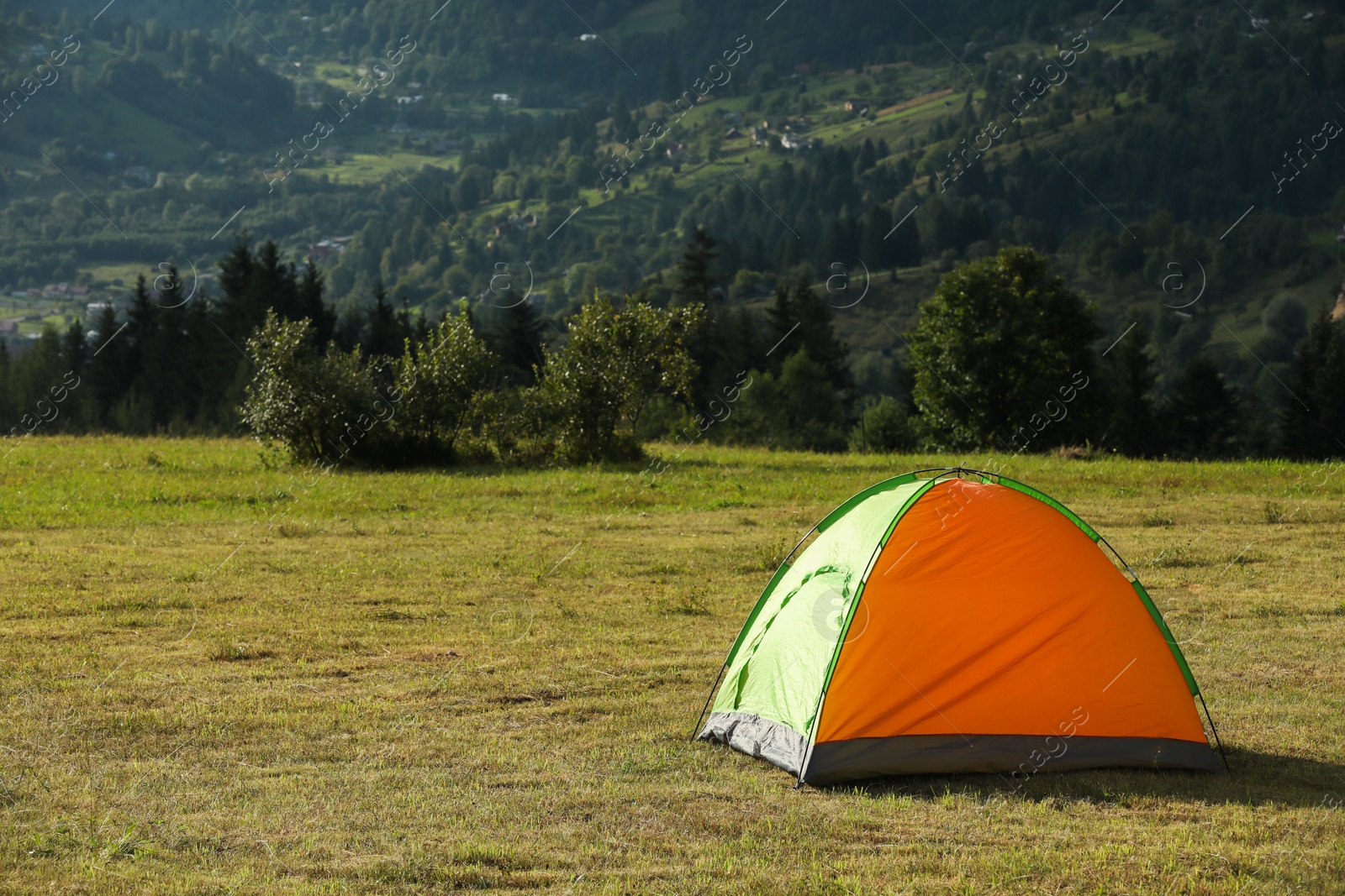 Photo of Tent on green grass in mountains, space for text