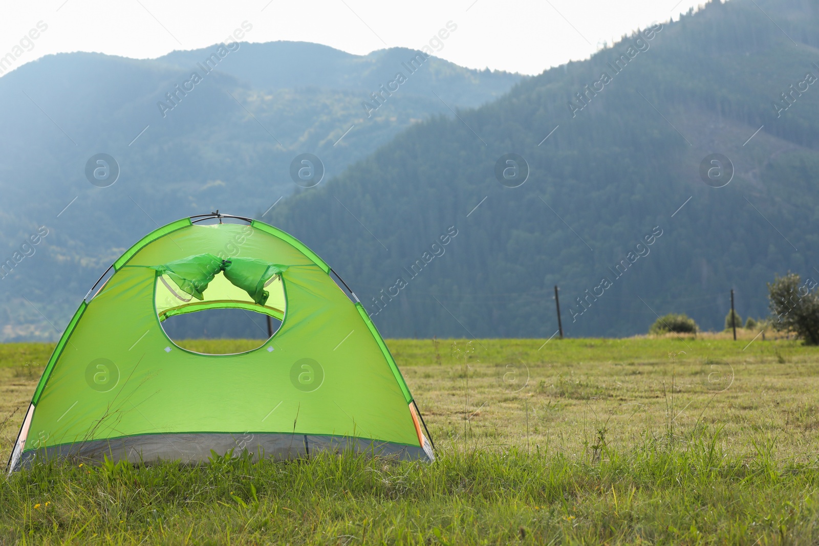 Photo of Tent on green grass in mountains, space for text