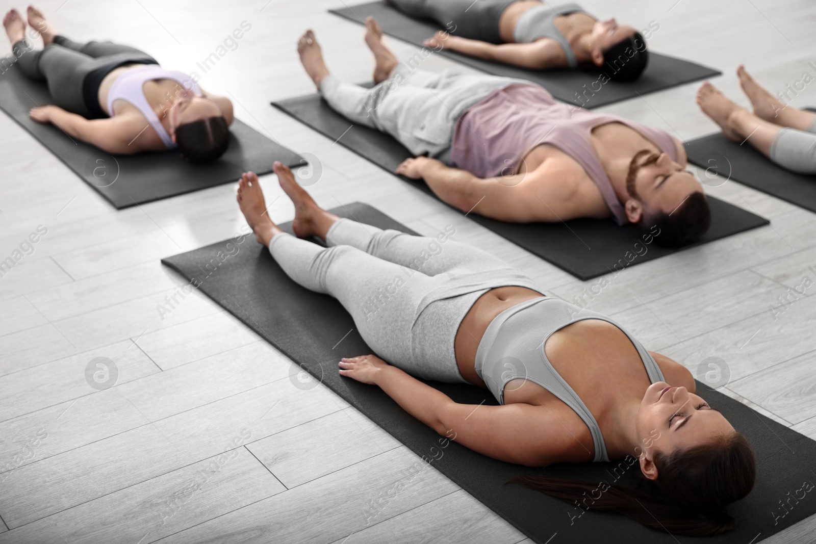 Photo of Group of people meditating on mats in yoga class