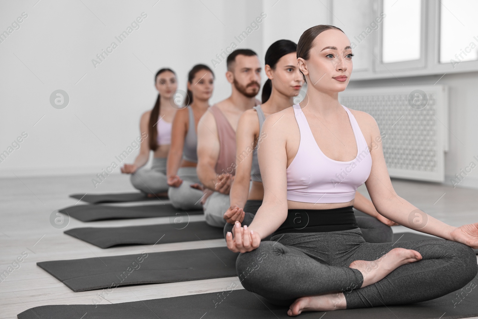 Photo of Group of people meditating on mats in yoga class