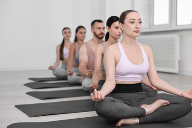 Photo of Group of people meditating on mats in yoga class